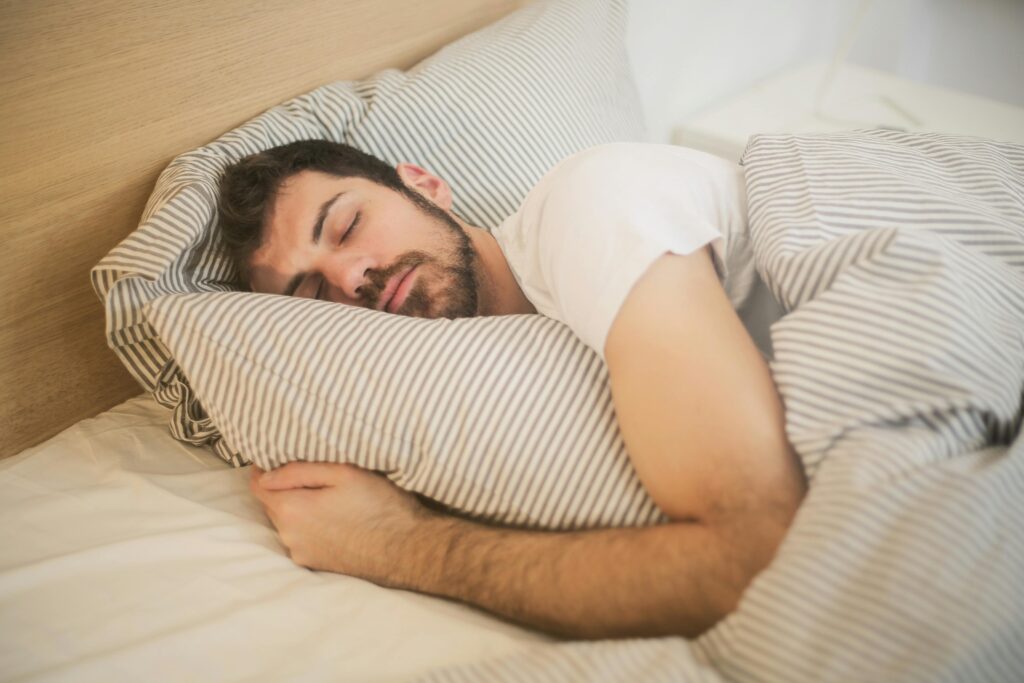 pexels-photo-3771069-3771069-1 Man sleeping peacefully on striped bedding, embracing relaxation and comfort.