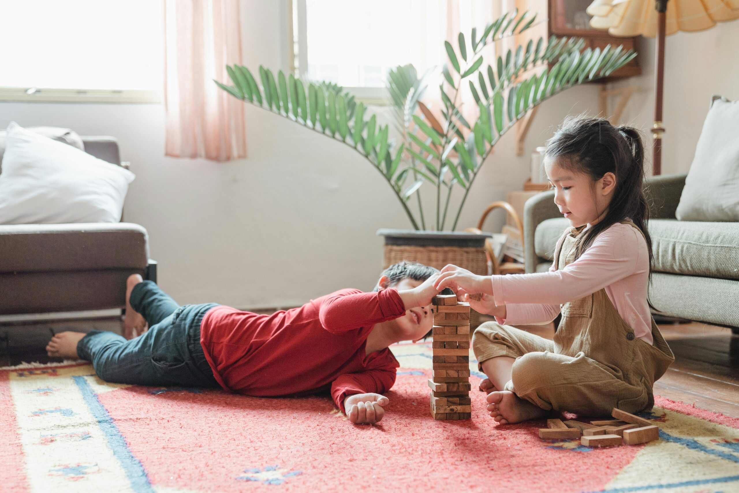 Two children playing Jenga in a cozy living room setting, enhancing their creativity and cognitive skills.